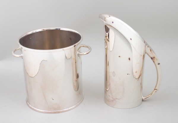 Lote contendo balde para gelo e jarra em metal da marca ST. James, medindo a jarra 26 cm de altura e o balde 19 cm de altura; apresentam sinais de uso, riscos superficiais, pontos de oxidação e marcas