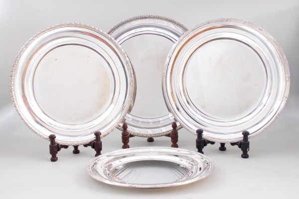Lote com 4 bandejas redondas Wolff em metal prateado, com bordas decoradas em relevos, medindo a maior 37 cm de diâmetro; apresentam sinais de uso, marcas do tempo, riscos superficiais e pequenos desg