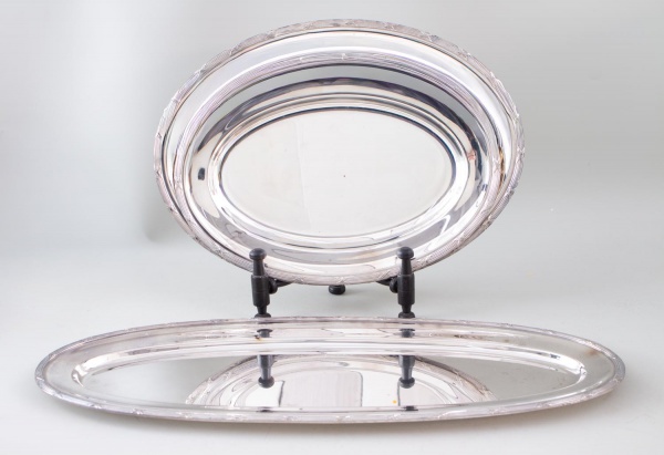 Lote contendo 3 travessas ovais em metal prateado da marca Wolff, medindo a maior 60 x 23 cm; apresentam sinais de uso, riscos superficiais, manchas e marcas do tempo.