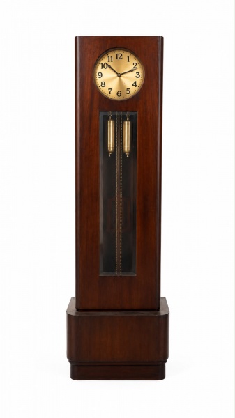 Relógio de coluna em madeira, mostrador circular metálico com numeração arábica, mecanismo de pêndulo e pesos aparentes, medindo 193 cm de altura, 63 cm de comprimento e 33 cm de profundidade; apresen