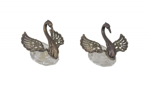 Par de saleiros em cristal com montagens em prata de lei teor 835, em formato de cisnes com asas vazadas e decoração floral; altura 8 cm; apresenta sinais de uso e marcas do tempo.