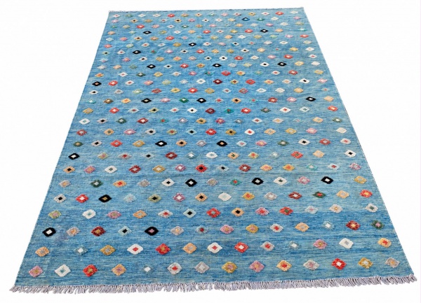 Tapete kilim em lã, fundo azul-claro com motivos geométricos multicoloridos, medindo 344 x 248 cm; apresenta sinais de uso, marcas do tempo e pequenos desgastes na trama.