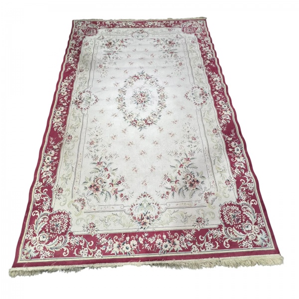 Tapete maquina com decoração floral em tons de creme, vinho, rosa e verde, medindo 300 x 194 cm; apresenta sinais de uso, desgastes nas franjas, pequenos pontos de desgaste nas bordas e marcas do temp
