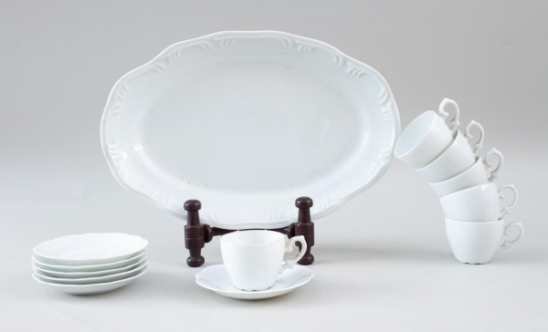 Conjunto de porcelana branca contendo 6 xícaras para café, 6 pires e 1 travessa oval medindo 33 x 22 cm, apresentando sinais de uso e marcas do tempo.