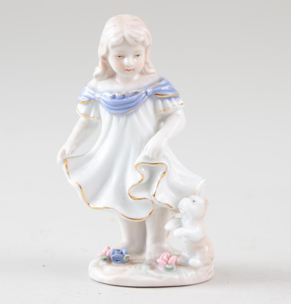 Escultura Lladró em porcelana espanhola, representando menina com vestido branco e detalhes em azul, acompanhada de urso e flores na base; marca Lladró na base; medindo 15 cm de altura; apresenta sina