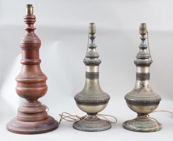 Lote contendo 3 bases para luminárias de mesa, sendo duas em metal com decoração em relevo e uma em madeira torneada. A maior medindo aproximadamente 66 cm de altura. Apresentam sinais de uso, marcas