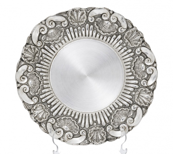 Prato decorativo em prata teor 833, com borda ricamente trabalhada em relevo com motivos concheados e volutas, medindo 30 cm de diâmetro e pesando 233 g; apresenta sinais de uso, riscos superficiais e