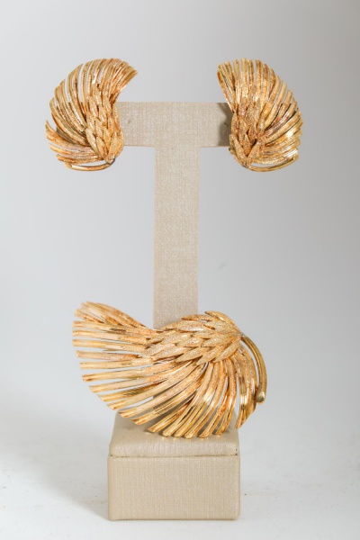 Conjunto em ouro amarelo 18K composto por broche e par de brincos em formato floral, com pétalas texturizadas e aplicação de rubis ao centro, pesando ao todo 20 g;
