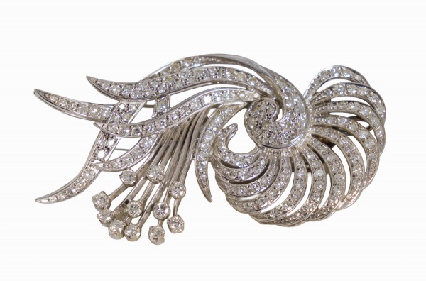 Broche em platina, com desenho estilizado em movimento espiralado e vazado, cravejado com diamantes em lapidação brilhante, pesando 15,8 g