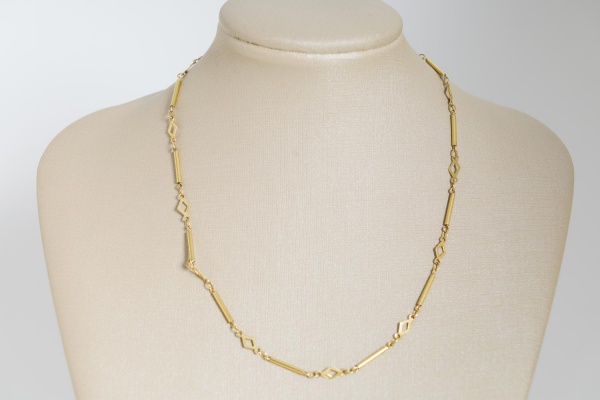 Colar em ouro amarelo 18K, composto por elos geométricos vazados intercalados por segmentos tubulares, com fecho tipo boia, pesando 5 g