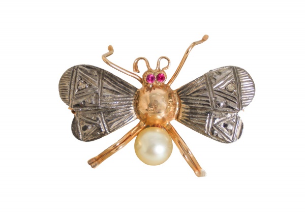 Broche em ouro 16k, pesando 2,9 g, em formato de abelha, com asas em metal branco ornamentadas por pequenos diamantes, olhos com rubis e pérola cultivada representando o corpo; peça delicada de joalhe