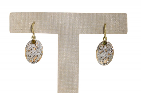 Par de brincos em ouro 18k, pesando 5,5 g, com pingentes ovais em ouro amarelo e ouro branco, decorados com delicado trabalho vazado e motivos florais em relevo, adornados por pequenas gemas verdes; f
