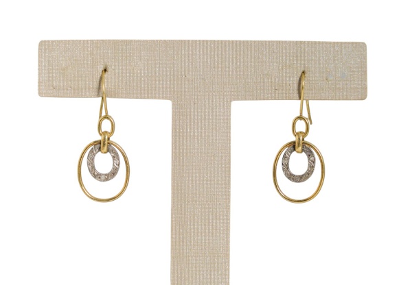 Par de brincos em ouro 18k, pesando 2,5 g, com design geométrico composto por elos ovais articulados em ouro amarelo e detalhe central em ouro branco com trabalho vazado e pequenos diamantes; fecho ti