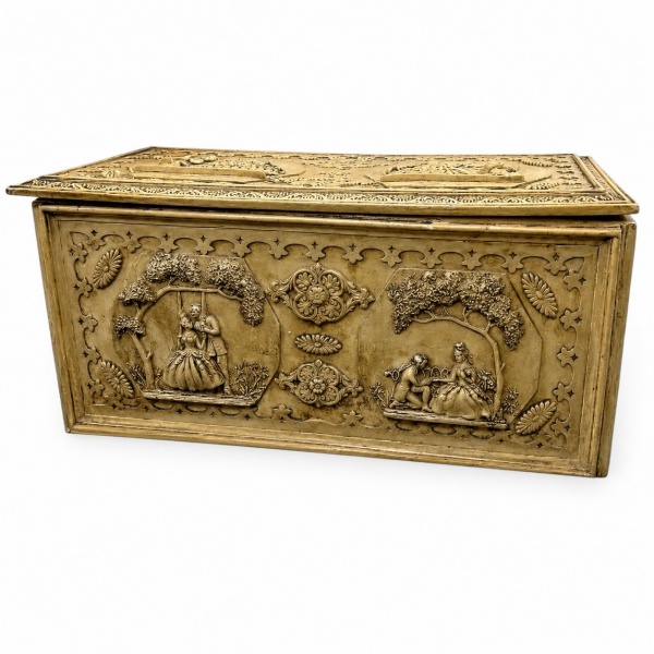 Baú decorativo em madeira revestido com placas em relevo de cenas galantes e motivos ornamentais, com tampa articulada e interior revestido; medindo 38 cm de altura, 43 cm de profundidade e 85 cm de l
