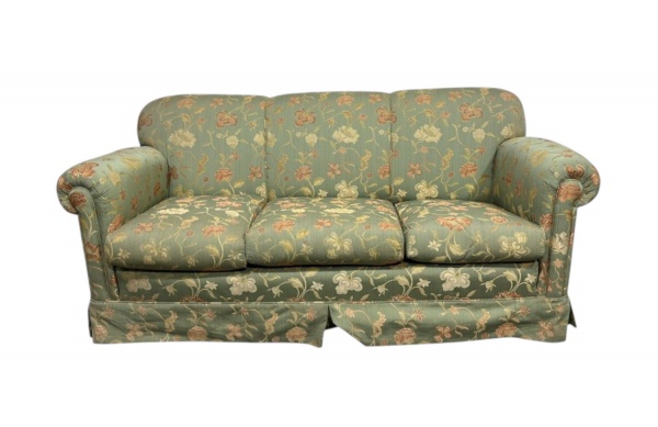 Sofá de três lugares, estofado com tecido floral em tons de verde, com almofadas soltas de assento, braços arredondados e saia; medindo 77 cm de altura, 80 cm de profundidade e 180 cm de largura; apre