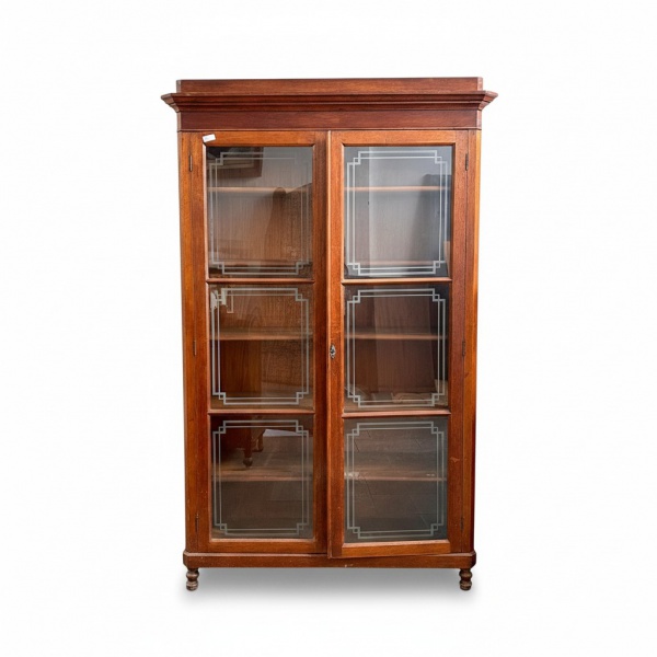 Cristaleira em madeira com duas portas envidraçadas, vidros decorados, prateleiras internas, frontão reto e pés torneados; medindo 215 cm de altura, 50 cm de profundidade e 140 cm de largura; apresent