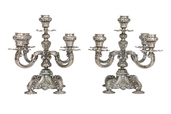 Par de candelabros em prata de lei, teor 800 milésimas, de cinco luzes cada, executados em estilo Barroco, com rico vocabulário ornamental em alto e baixo relevo. Cada peça assenta sobre base trípode