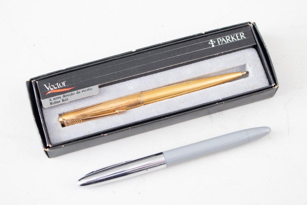Lote contendo 2 canetas, sendo uma caneta Parker Vector Roller Ball dourada acompanhada de estojo original e uma caneta esferográfica de corpo cinza com tampa cromada; apresentam marcas de uso, riscos