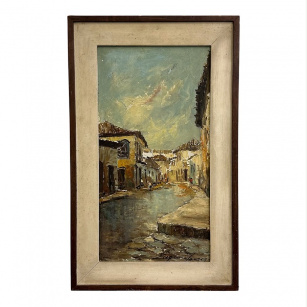 Quadro óleo sobre Eucatex, representando paisagem urbana com casario colonial e rua, assinado no canto inferior direito. Medidas: 47 x 29 cm (moldura) e 37 x 19 cm (obra). Apresenta marcas do tempo e