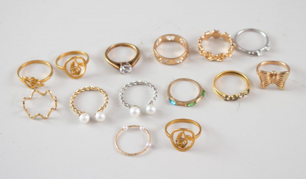 Lote com anéis femininos diversos; em metal dourado e prateado; com aplicações de pérolas e pedras sintéticas; em diferentes modelos e tamanhos; apresenta marcas de uso e sinais do tempo conforme foto
