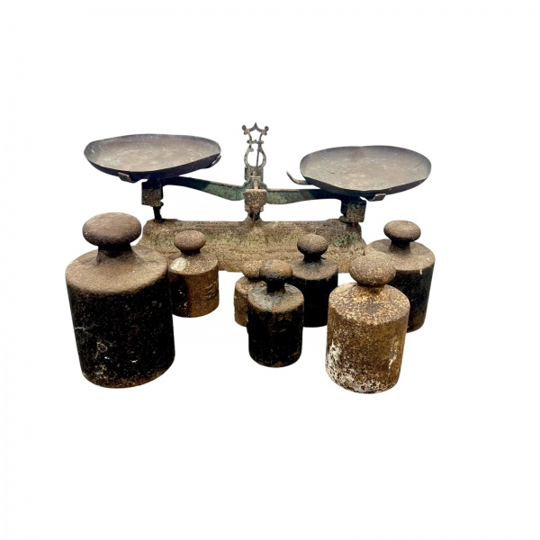 Balança antiga de dois pratos, em ferro fundido, acompanhada por 7 pesos de aferição em ferro de diferentes medidas, conjunto utilizado para pesagem comercial. Peça de caráter decorativo e colecionáve