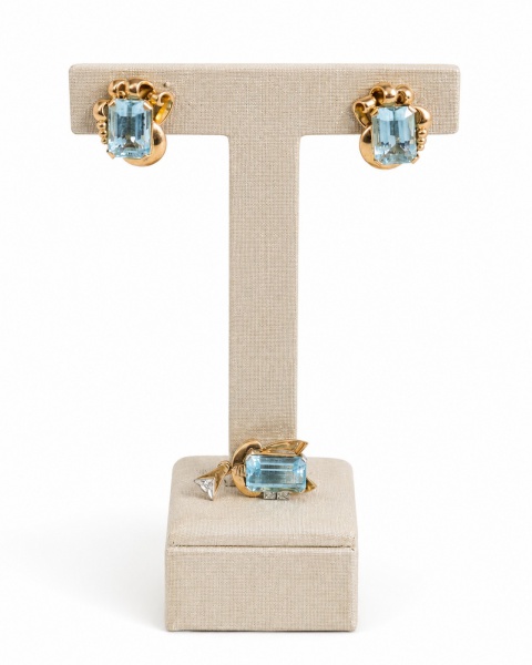Conjunto em ouro amarelo 18k, composto por par de brincos de pressão e pingente, adornados com pedras centrais de tonalidade azul em lapidação retangular facetada, possivelmente água-marinha ou topázi