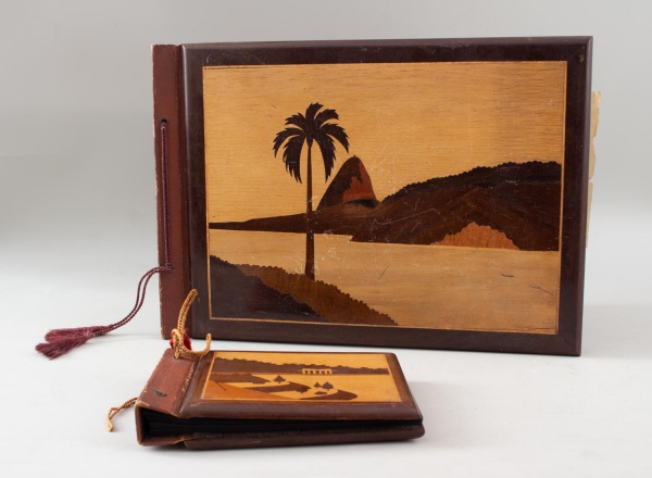 Lote composto por 2 álbuns porta-fotografias antigos, com capas em madeira decoradas por marchetaria representando paisagens. O maior mede 42 30 cm. Apresentam folhas internas, sinais de uso, desgaste