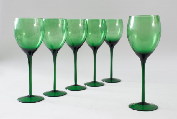 Conjunto com 6 taças para vinho em vidro verde translúcido, com bojo liso e haste alongada, medindo 23 cm de altura cada, apresentando leves marcas de uso compatíveis com a conservação.