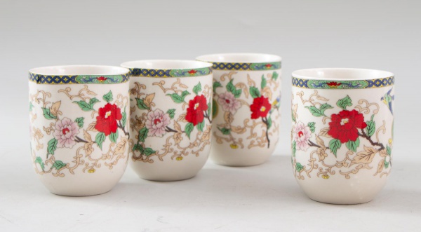 Conjunto com 4 copos orientais para saquê em porcelana, decorados com motivos florais policromados e arabescos em dourado, com marca em caracteres orientais na base, medindo 8 cm de altura cada, apres