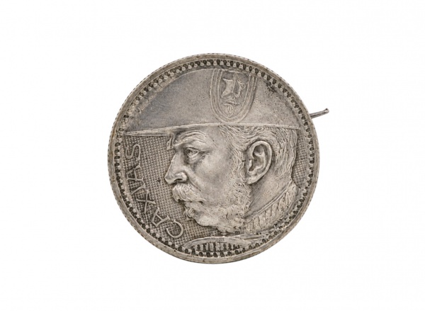 Broche composto por moeda brasileira de 2000 réis, datada de 1935, em prata 900/1000, anverso com efígie alegórica da República tocada por raios solares, reverso com espada em cruz sobre a legenda de