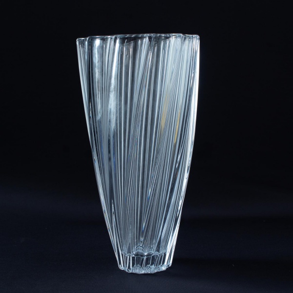 Vaso em cristal incolor, de corpo alto com decoração em relevo de frisos verticais facetados, conferindo elegante efeito óptico. Mede 30 cm de altura. Apresenta marcas de uso e conservação compatíveis