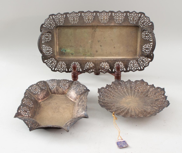 Lote composto por uma bandeja e duas fruteiras em metal prateado, com bordas vazadas e decoração rendilhada, incluindo modelos retangular, sextavado e circular. Maior peça medindo 38 cm de comprimento