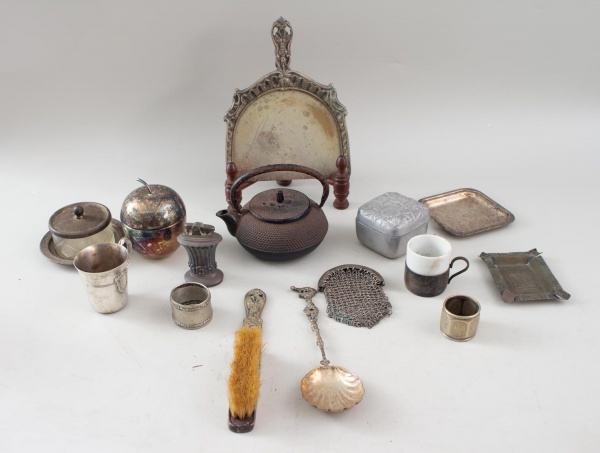 Lote desconjuntado composto por utensílios e objetos decorativos em metais diversos, incluindo escova, concha, bandeja, chaleira de ferro fundido, porta-objetos, recipiente com tampa, canecas, cinzeir