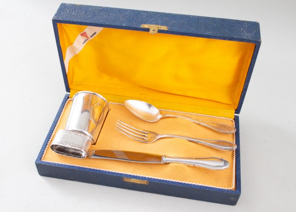 Faqueiro da marca Eberle, acondicionado em estojo original revestido, composto por copo, colher, garfo e faca em metal, com monograma gravado no copo, e porta guardanapo - vendido no estado em que se