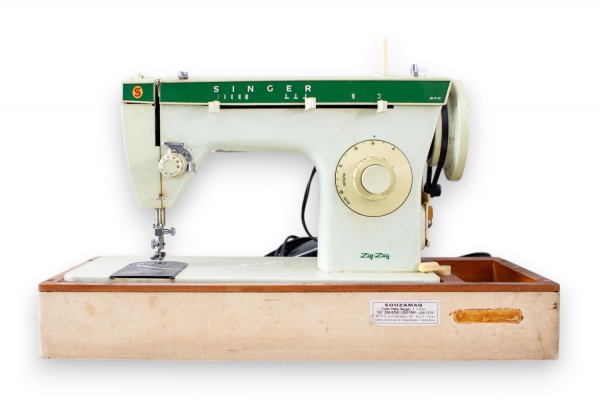 Máquina de costura Singer modelo 242, de fabricação brasileira, com gabinete portátil em madeira e tampa revestida, acompanhada de pedal elétrico e manual de instruções original, vendida no estado em 