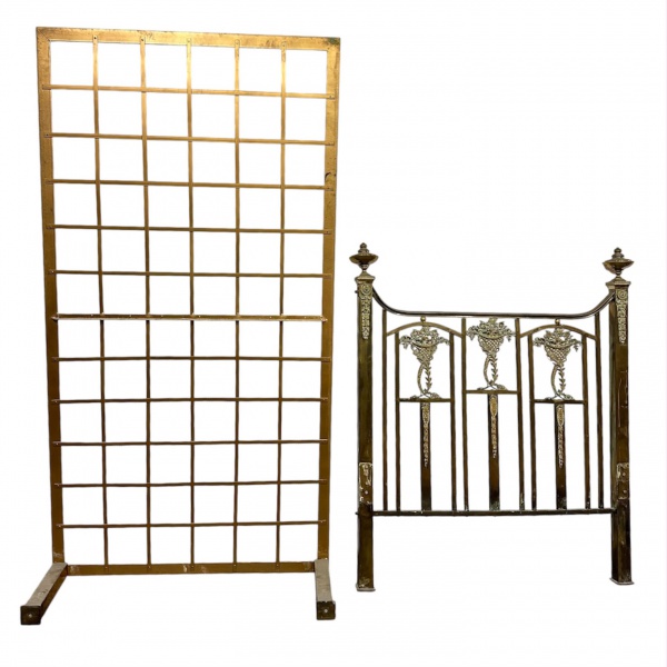 Cama de solteiro em metal com acabamento em tom dourado envelhecido, composta por cabeceira e peseira com elementos decorativos em relevo de inspiração clássica, apresentando cestos florais e guirland