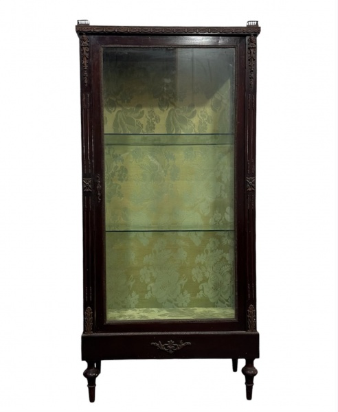 Cristaleira em madeira com porta de vidro, laterais envidraçadas, interior revestido em tecido estampado e duas prateleiras de vidro. Possui chave e elementos decorativos em metal. Mede 129 cm de altu