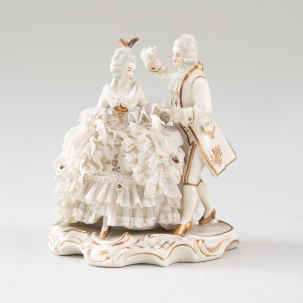 Escultura em porcelana Dresden-Art (Alemanha) representando casal em trajes de época, com aplicações rendadas em tecido e detalhes dourados. Base marcada Dresden-Art Made in Germany. Medindo 17 cm de