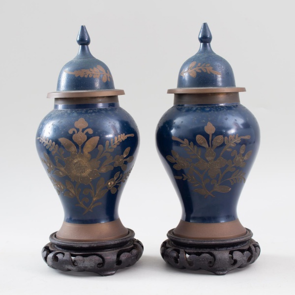Par de potiches decorativos em metal com acabamento azul e decoração floral gravada, com tampas e bases entalhadas, medindo 26 cm de altura cada, apresentando marcas do tempo e desgastes compatíveis c