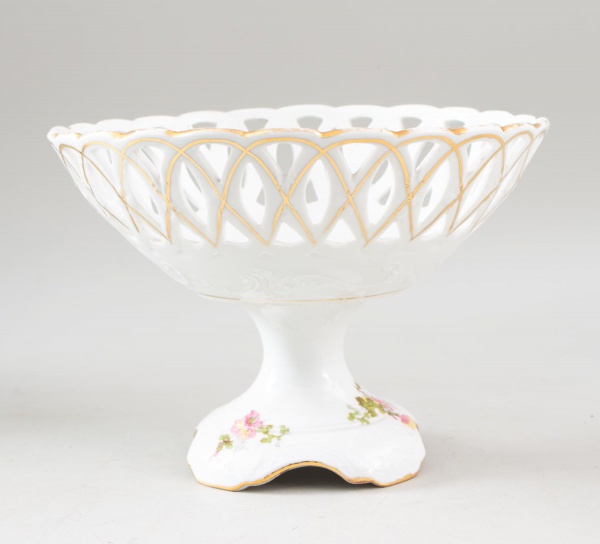 Centro de mesa em porcelana francesa Limoges, com borda vazada, decoração floral policromada e filetes dourados, apoiado sobre pé elevado, medindo 18 cm de altura e 24 cm de diâmetro, apresentando des