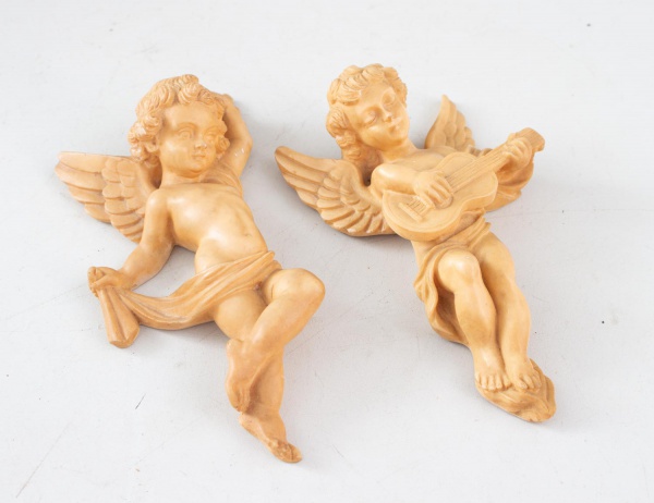 Par de esculturas de anjos em resina, sendo um com instrumento musical e outro em pose decorativa, próprias para fixação em parede; altura: 15 cm cada; apresentam marcas do tempo e desgastes naturais.
