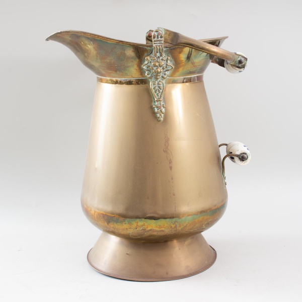Calha de carvão de latão antigo, com alças articuladas e pegadores em porcelana, borda recortada e aplicações decorativas em relevo; medidas: 40 cm de altura e 32 cm de comprimento; apresenta marcas d