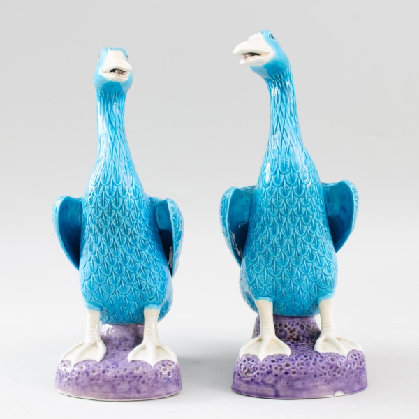 Par de esculturas em porcelana esmaltada representando aves aquáticas, em tons de azul e branco sobre base em relevo; altura: 25 cm cada; apresentam marcas do tempo e desgastes.