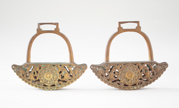Par de estribos antigos em bronze com decoração vazada em relevo, apresentando motivo de estrela central e arabescos. Medindo 16 cm de altura e 18 cm de comprimento. Apresentam pátina, oxidação e marc