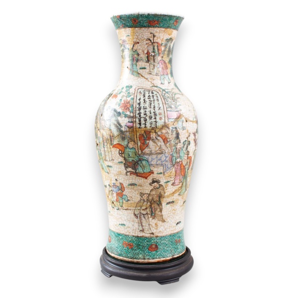 Grande vaso em porcelana oriental decorada com figuras em cenas palacianas, paisagens e inscrições, com acabamento craquelado e base em madeira. Medindo 64 cm de altura. Apresenta trincas, restauros,