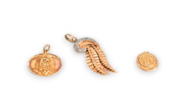 Lote composto por três pingentes em ouro 16K: medalha circular com imagem em relevo de Nossa Senhora de Guadalupe, auréola raiada e figura sobre lua crescente, verso liso sem gravação; pingente em des