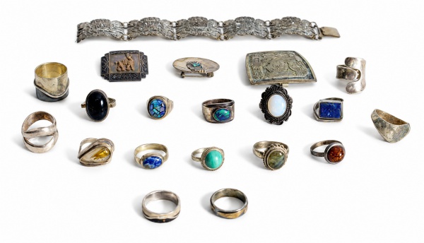 Lote composto por 20 peças em prata de lei, sendo pulseira articulada, broches e anéis, alguns com aplicações de pedras naturais e sintéticas em diferentes formatos e cores, com decoração em relevo. P