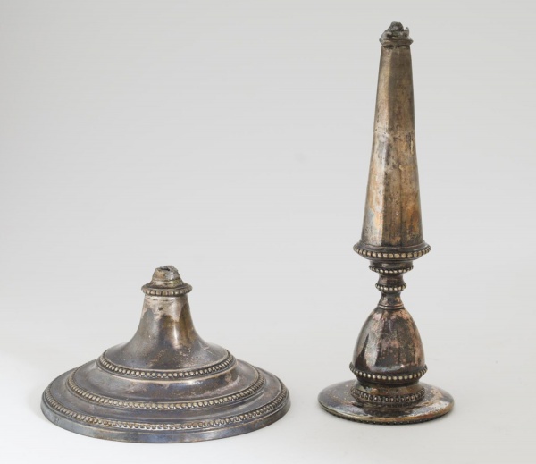 Castiçal em prata de lei, teor 833, de corpo torneado com decoração em frisos de contas e base circular escalonada. Peso: 367 g. Apresenta quebra na haste, além de marcas de uso, oxidação e desgastes