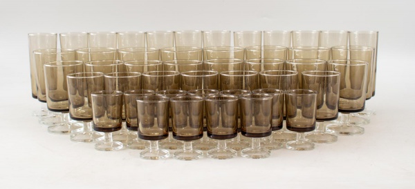 Lote composto por 57 taças em vidro fumê de fabricação francesa (France), composto por modelos para água, vinho, licor e espumante, em tamanhos variados. Maior peça medindo 14 cm de altura. Apresentam