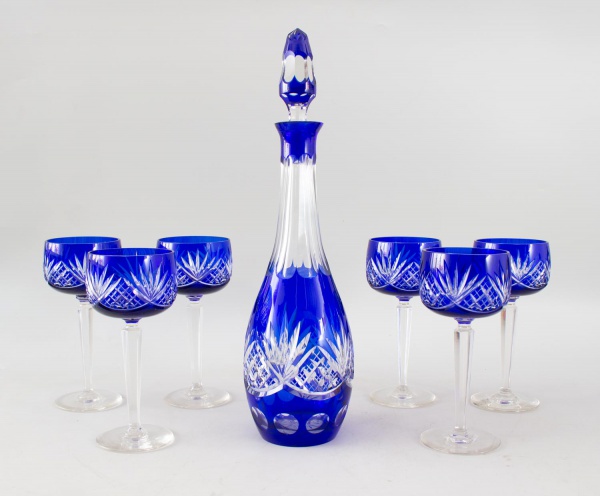 Conjunto em cristal Baccarat azul cobalto lapidado, composto por licoreira com tampa e 6 taças, decorado com rica lapidação geométrica e floral, evidenciando a transparência e o brilho característicos